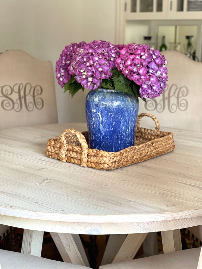 purple hydrangeas in a blue vase on a tray on table