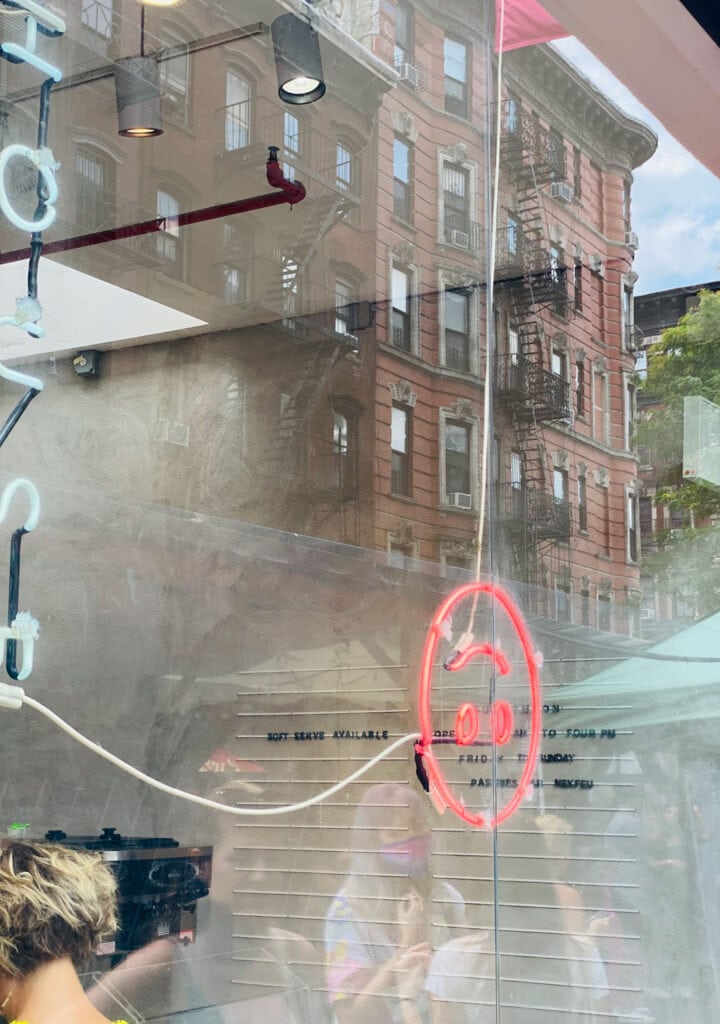 A fluorescent upside down smile face sign hangs in the window of the East Village's Supermoon Bakehouse.