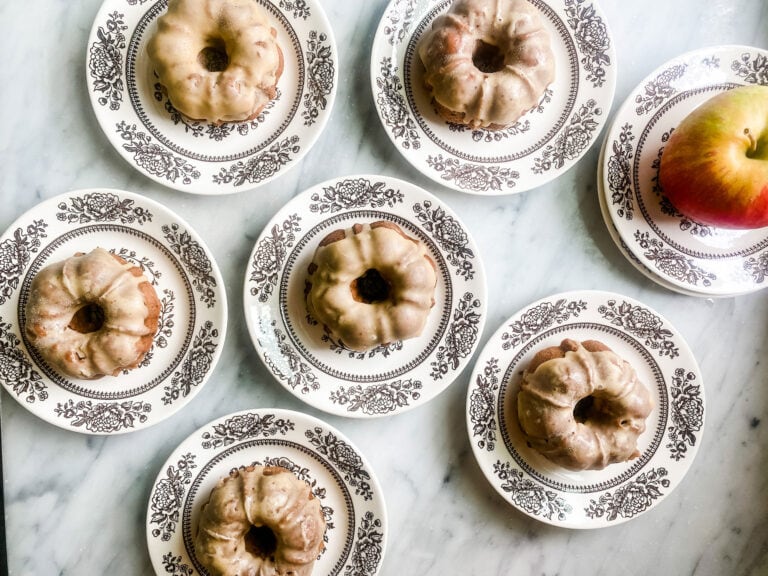 Baked apple cider doughnuts have a maple glaze topping and are served on small plates with brown floral designs.