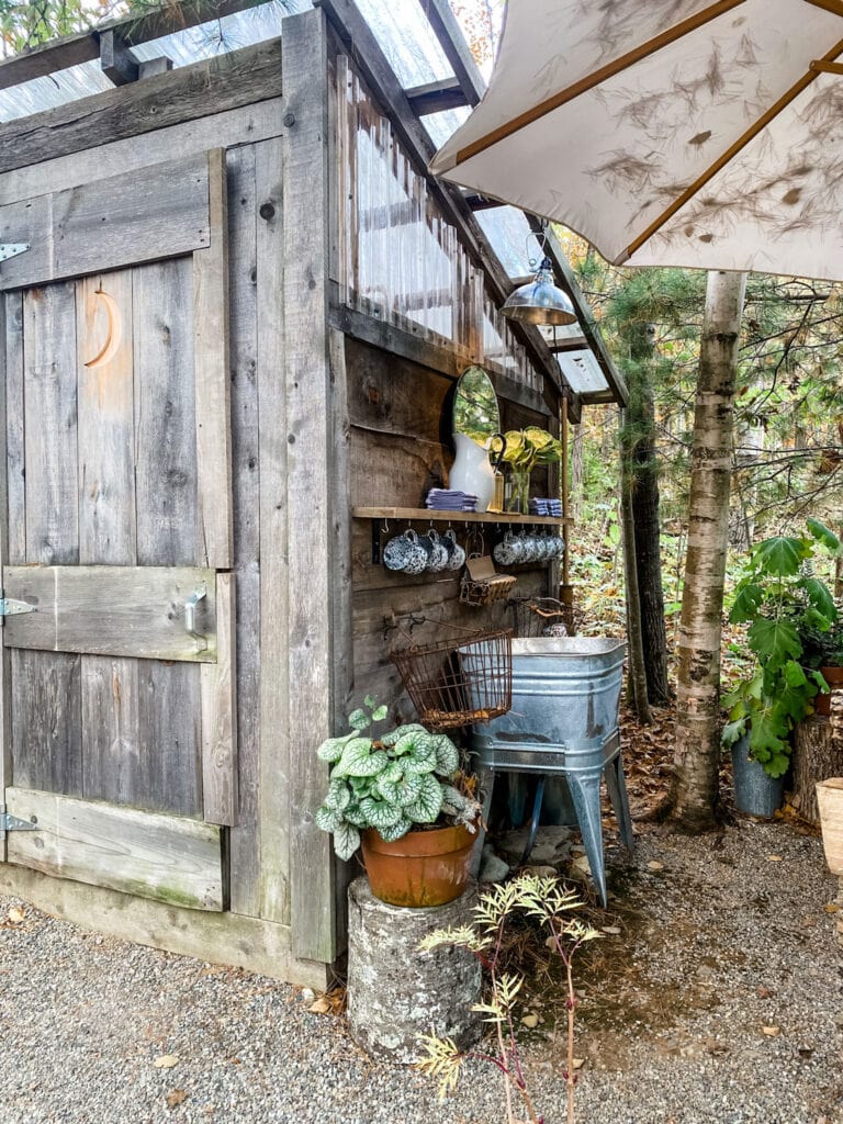 enamel mugs, pitcher, flowers, mirror at the lost kitchen outhouse in the woods