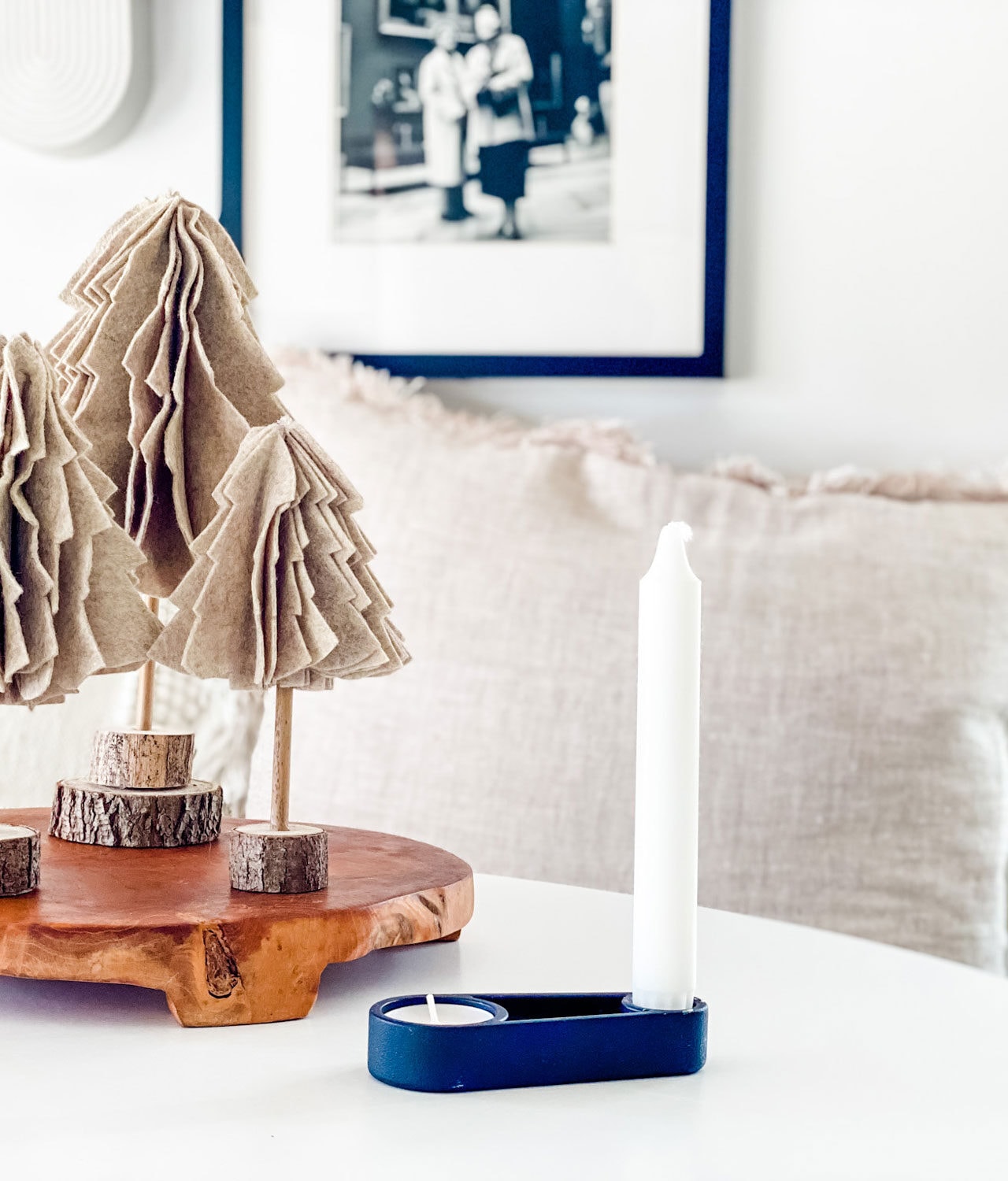 felt tree on wood bases on wood trivet on white table with black candle holder