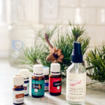 A small bottle and essential oil on counter with pine tree limb