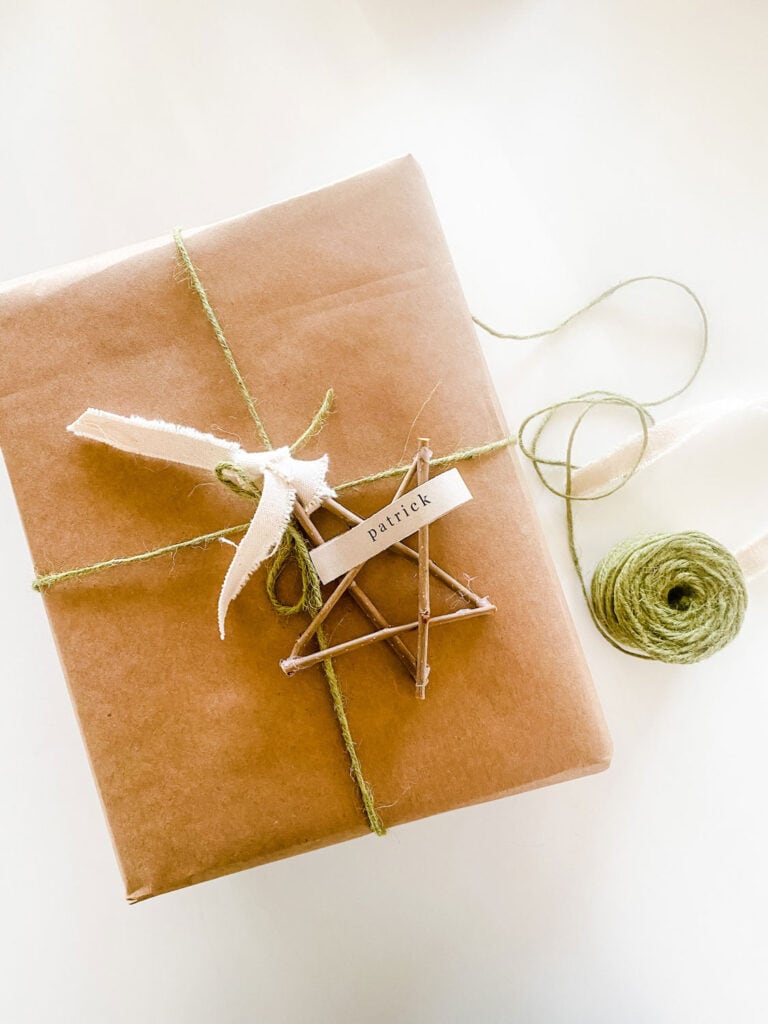 A present is wrapped in kraft paper and jute twine. The twig star is attached with frayed canvas ribbon.