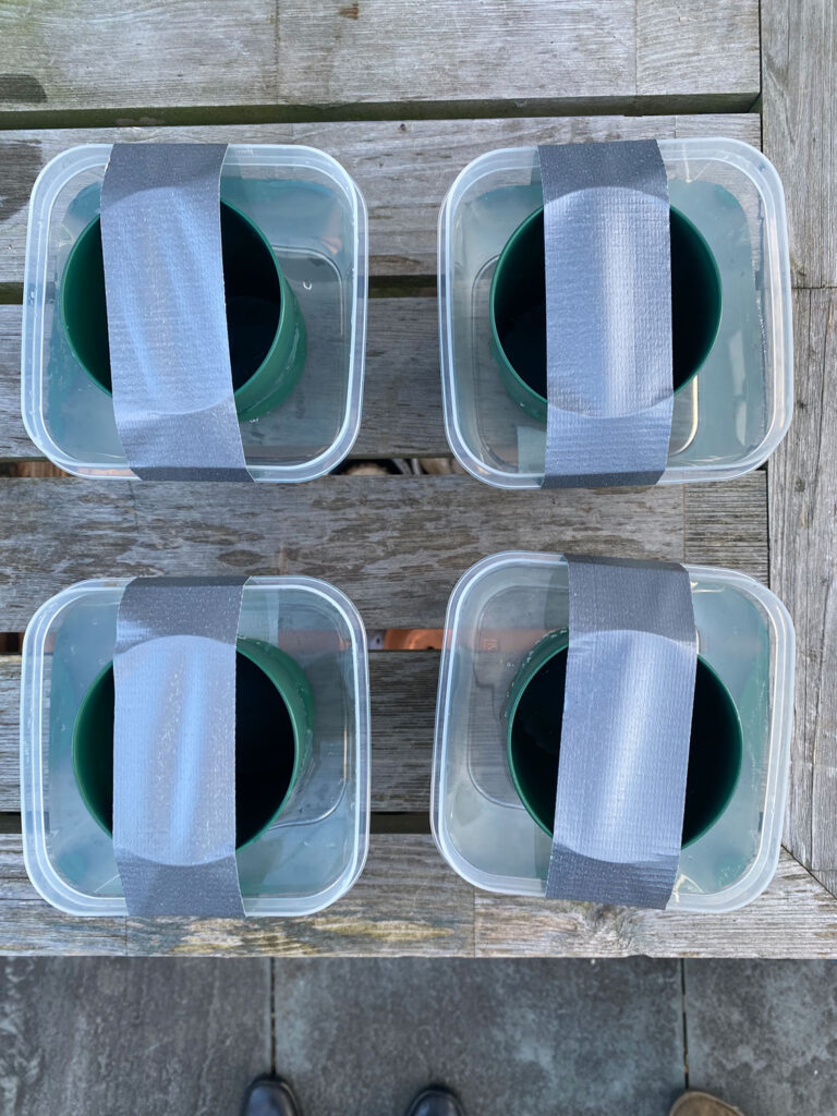 containers with green cups and tape on bench
