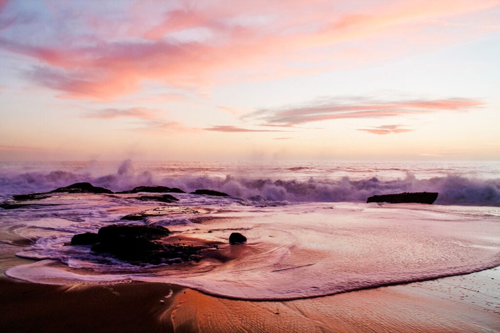 Pink and orange beach skies with waves make a beautiful Laguna Beach sunset.