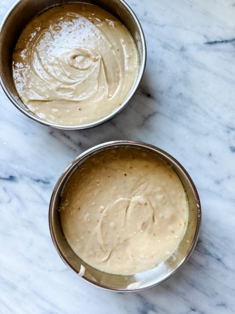 Cake batter has been poured into two small six round cake pans.