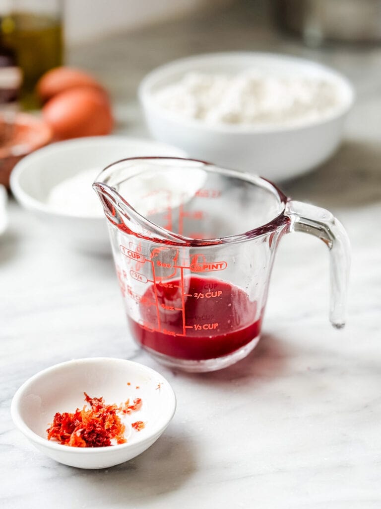 Blood orange juice is in a measuring cup, and the zest is in a small white dish.