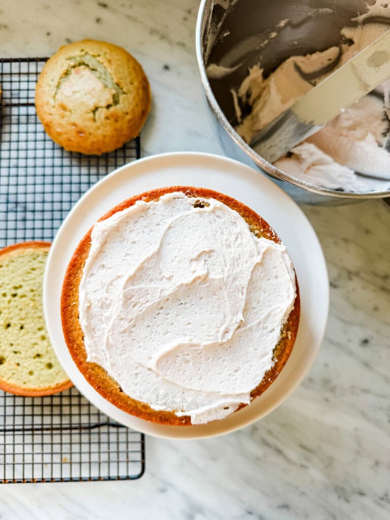 The middle layer of blood orange olive oil cake has been topped with butter cream frosting.