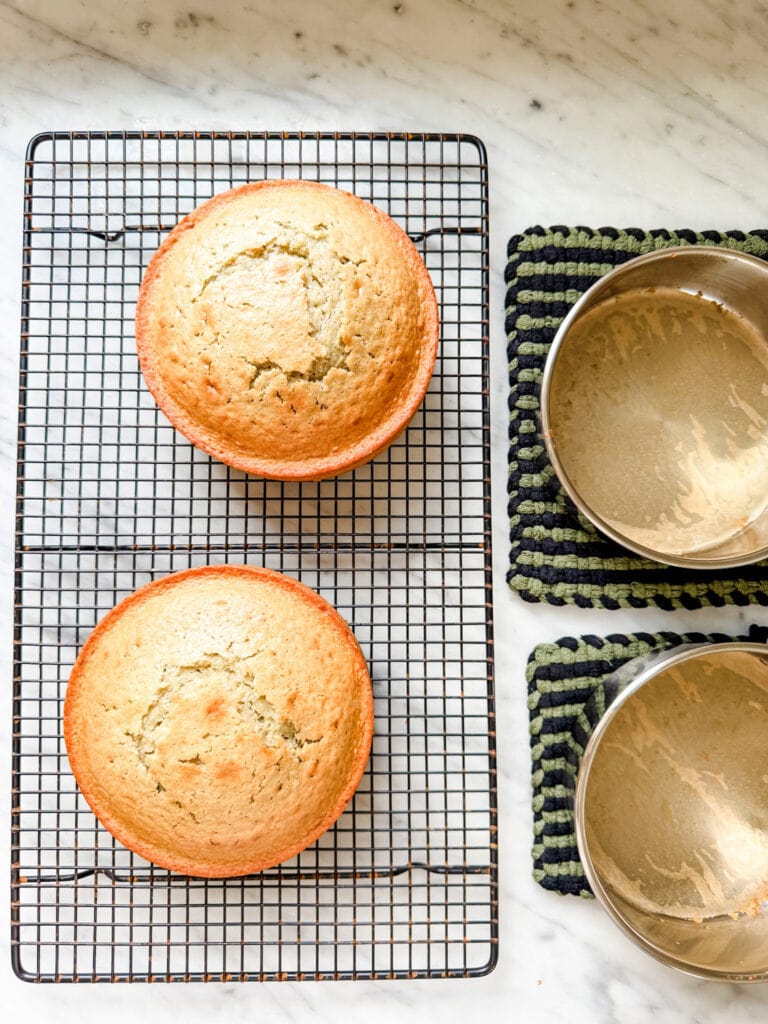 Two small cakes have been baked and are cooling on a wire rack.