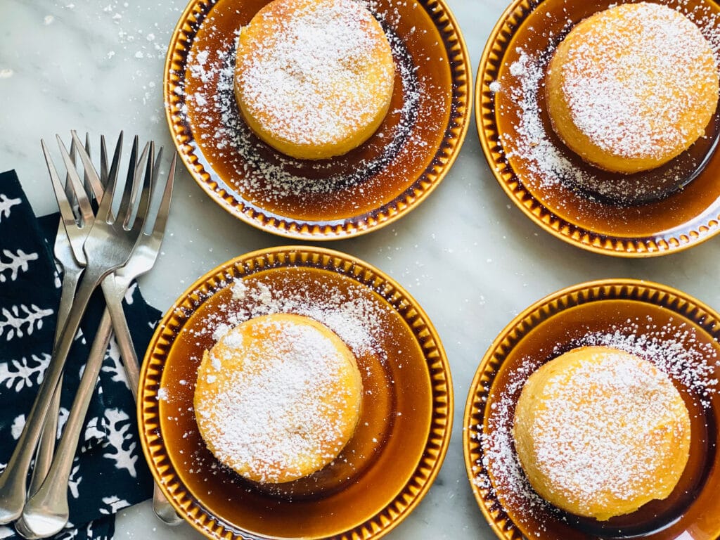 The best lemon lava cakes if you love lemon are sprinkled with powdered sugar and served on small brown plates.
