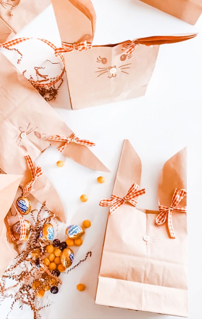 Four paper bag Easter bunnies are filled with treats and goodies.