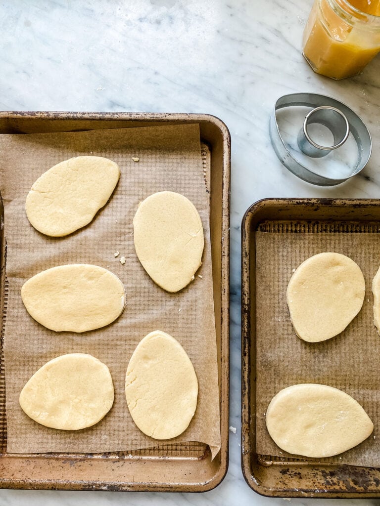Egg-shaped shortbread cookie dough on parchment-lined baking sheet.