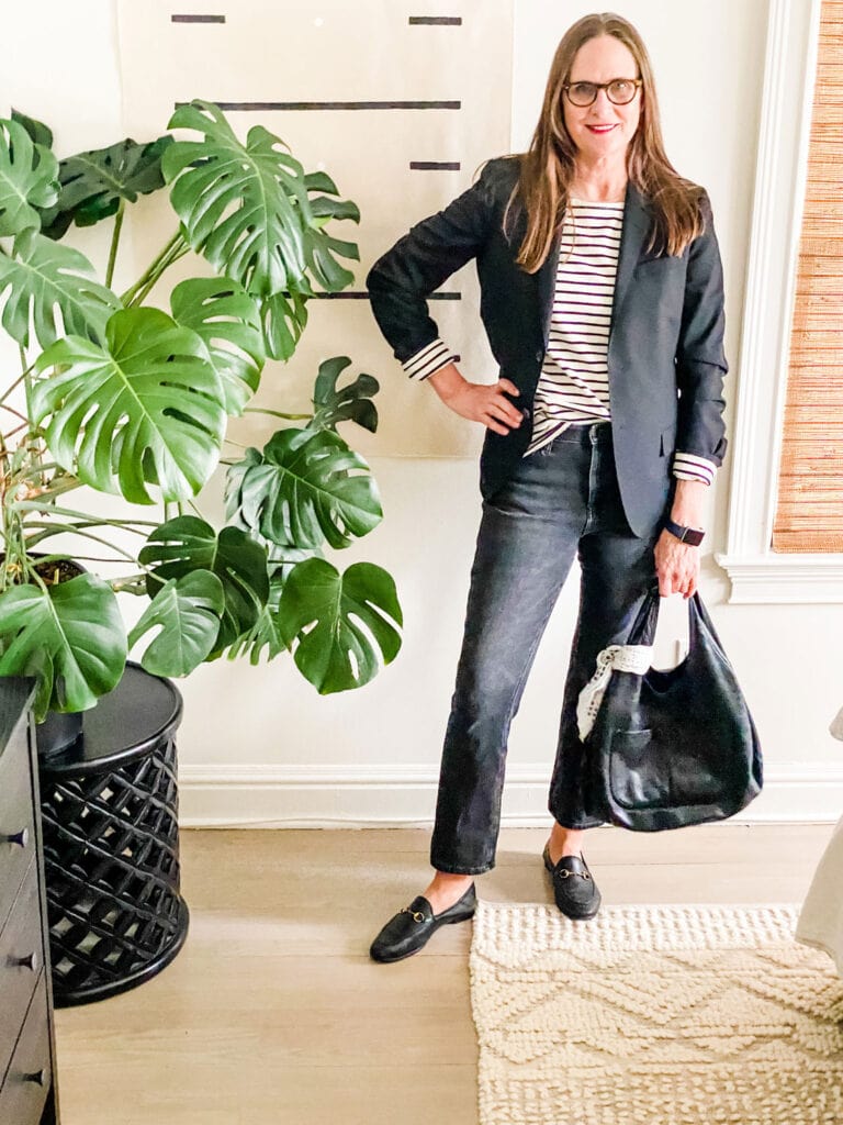 Off Black Jeans, Stripes and Gucci loafers on woman next to large plant