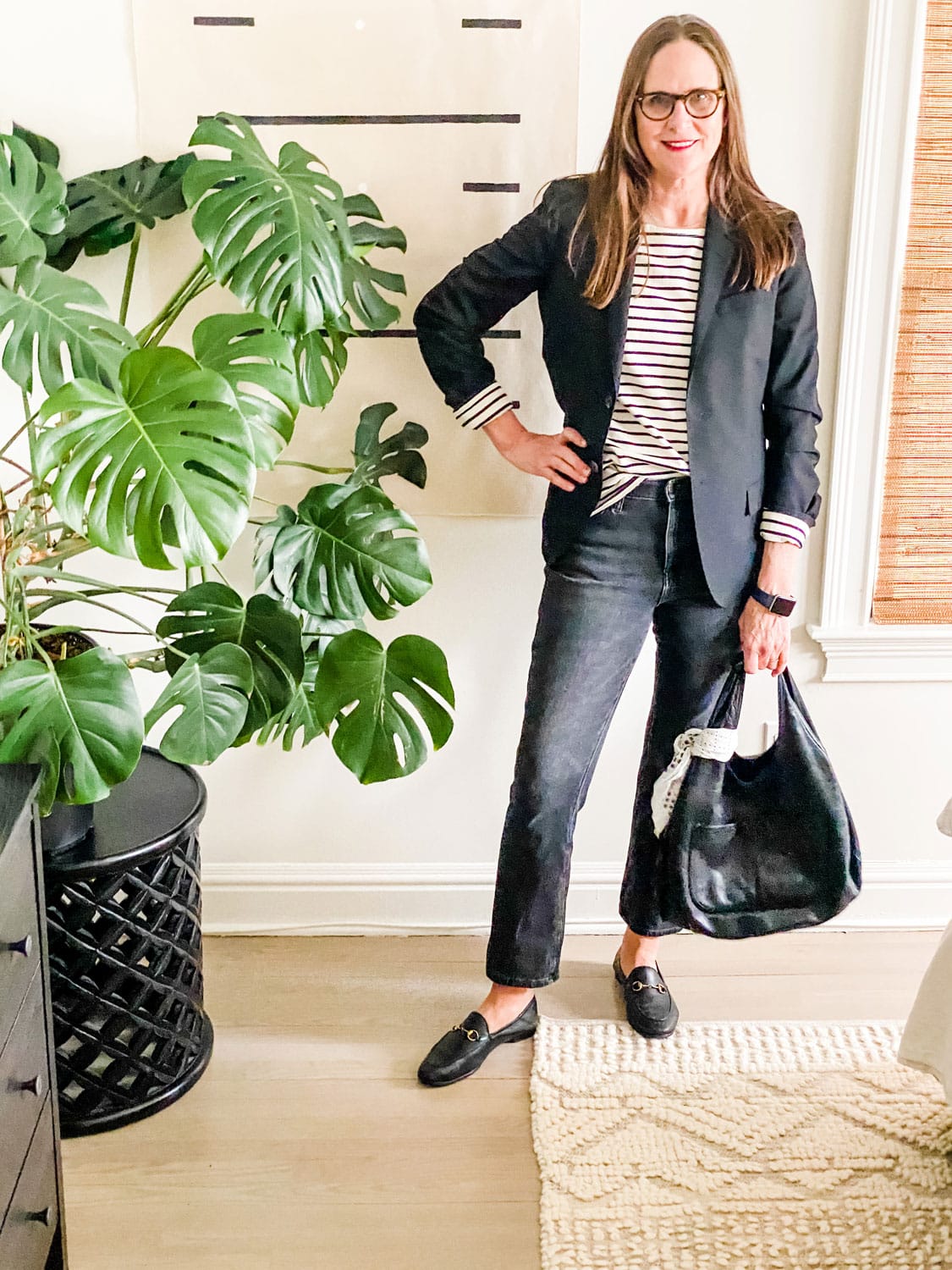 Off Black Jeans, Stripes and Gucci loafers on woman next to large plant