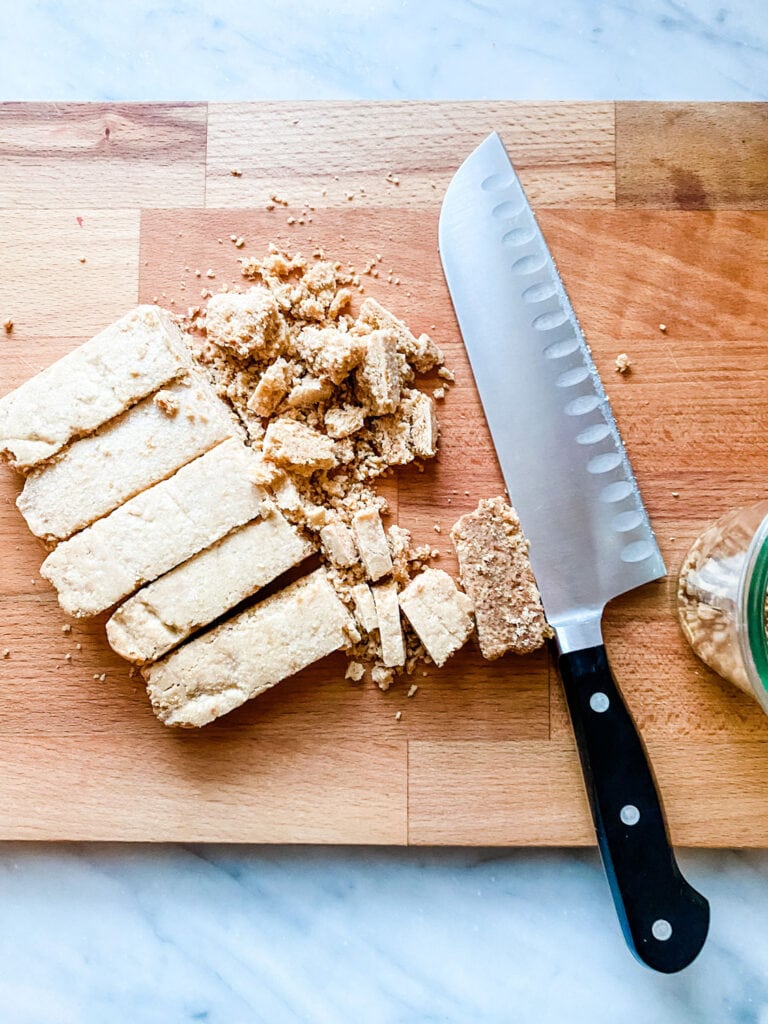 Twice-baked shortbread on a cutting board being crumbled to make Britains famous Humble Crumble dessert.