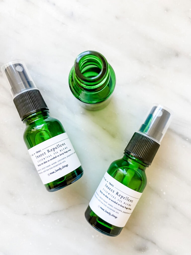 Three 15 ml green bottles, two with spray tops, filling with all-natural bug spray made from essential oils