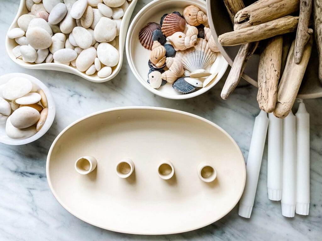 shells, white ticks driftwood, candles in bowls on marble counter with tray