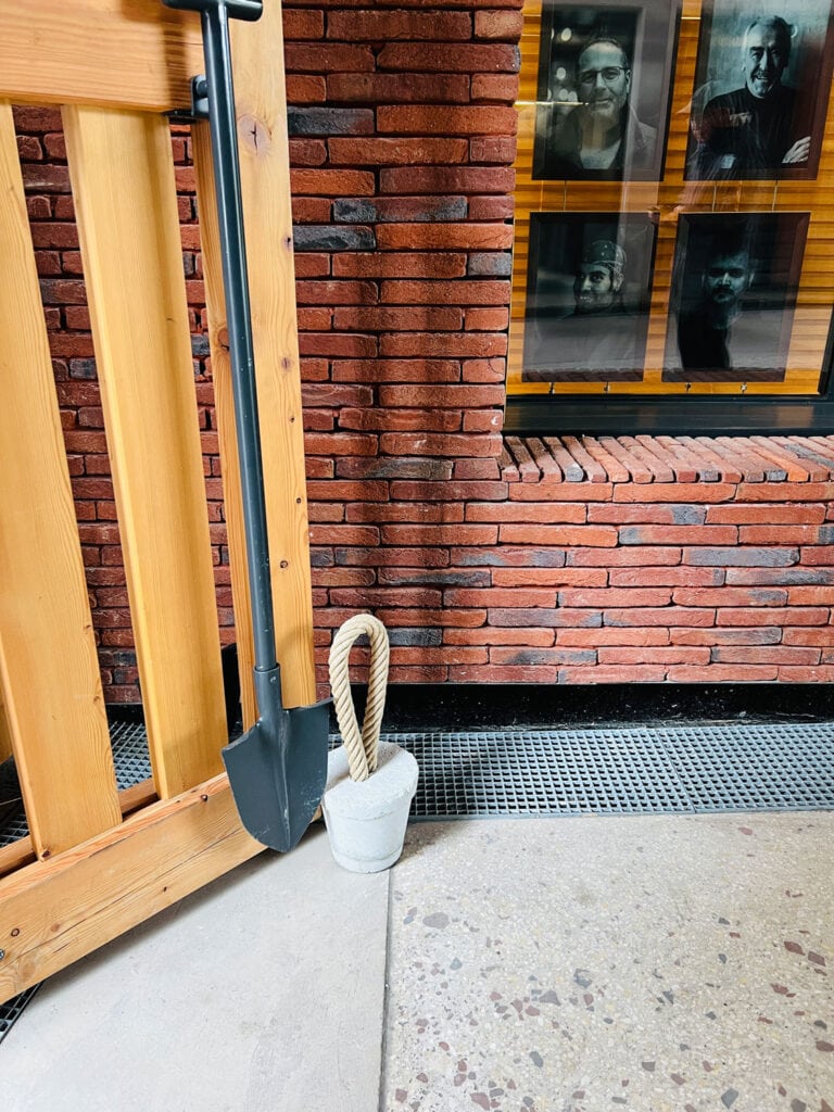 door to hotel with a shovel for a handle and a cement door stopper with rope handle