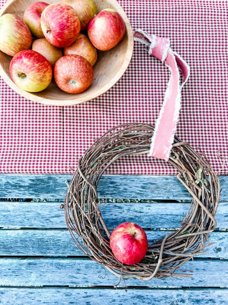 bowl of apples, wreath with ribbon on checked fabric