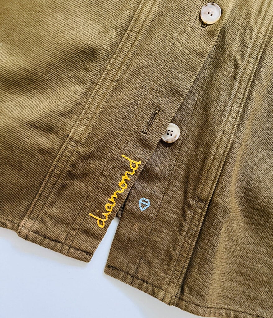 A close up of a name embroidered on the front of a Sezane chore coat
