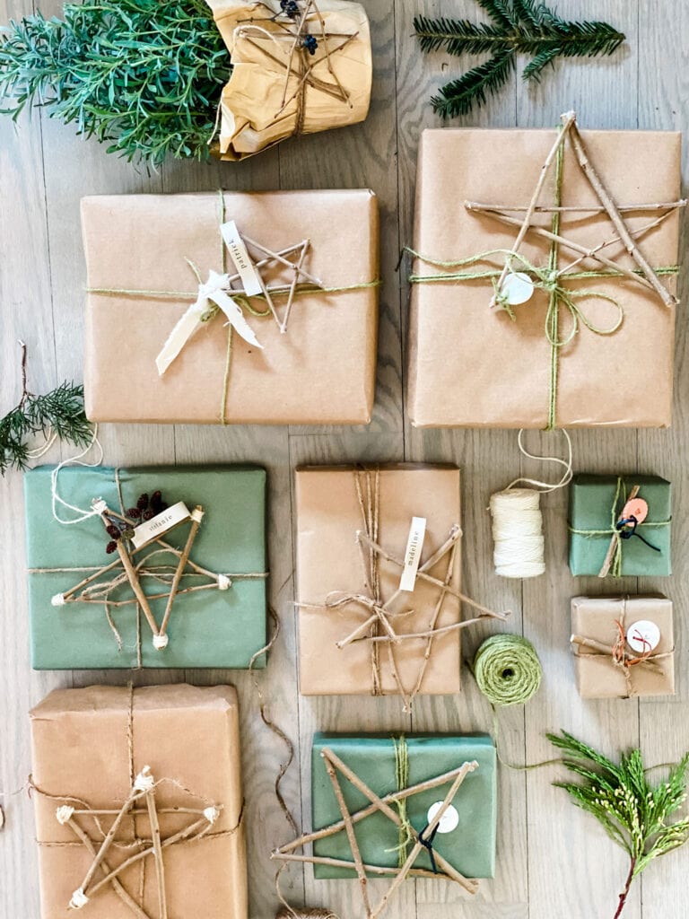 9 presents wrapped in green and brown Kraft paper with different shades of twine and twig stars used for gift tags.