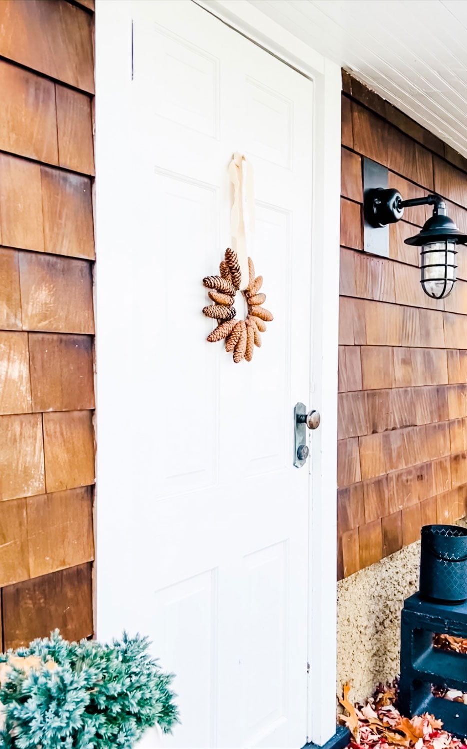 A simple pinecone wreath on a white door