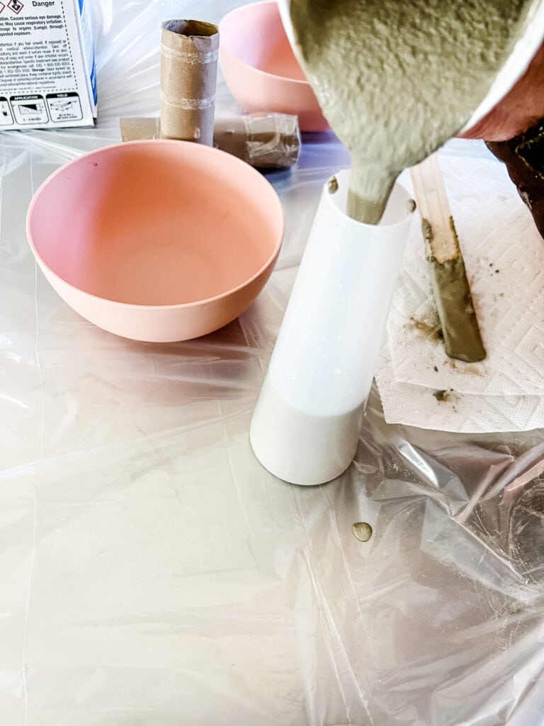 Cement is being poured into a mold to form the stem of an easy DIY concrete mushroom for the garden.