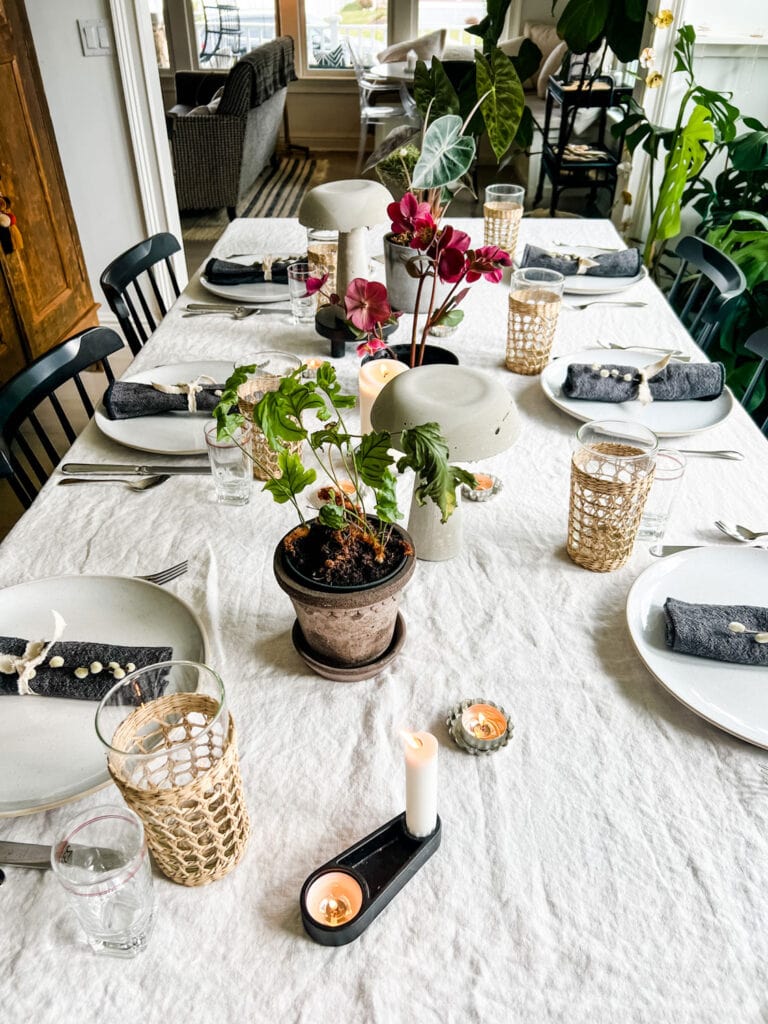 A dinner party tablescape featuring concrete mushrooms and potted plants.