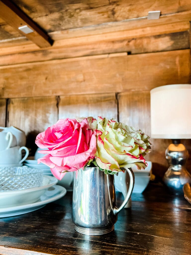 garden roses to a vintage hotel silver pitcher in armoire made of wood
