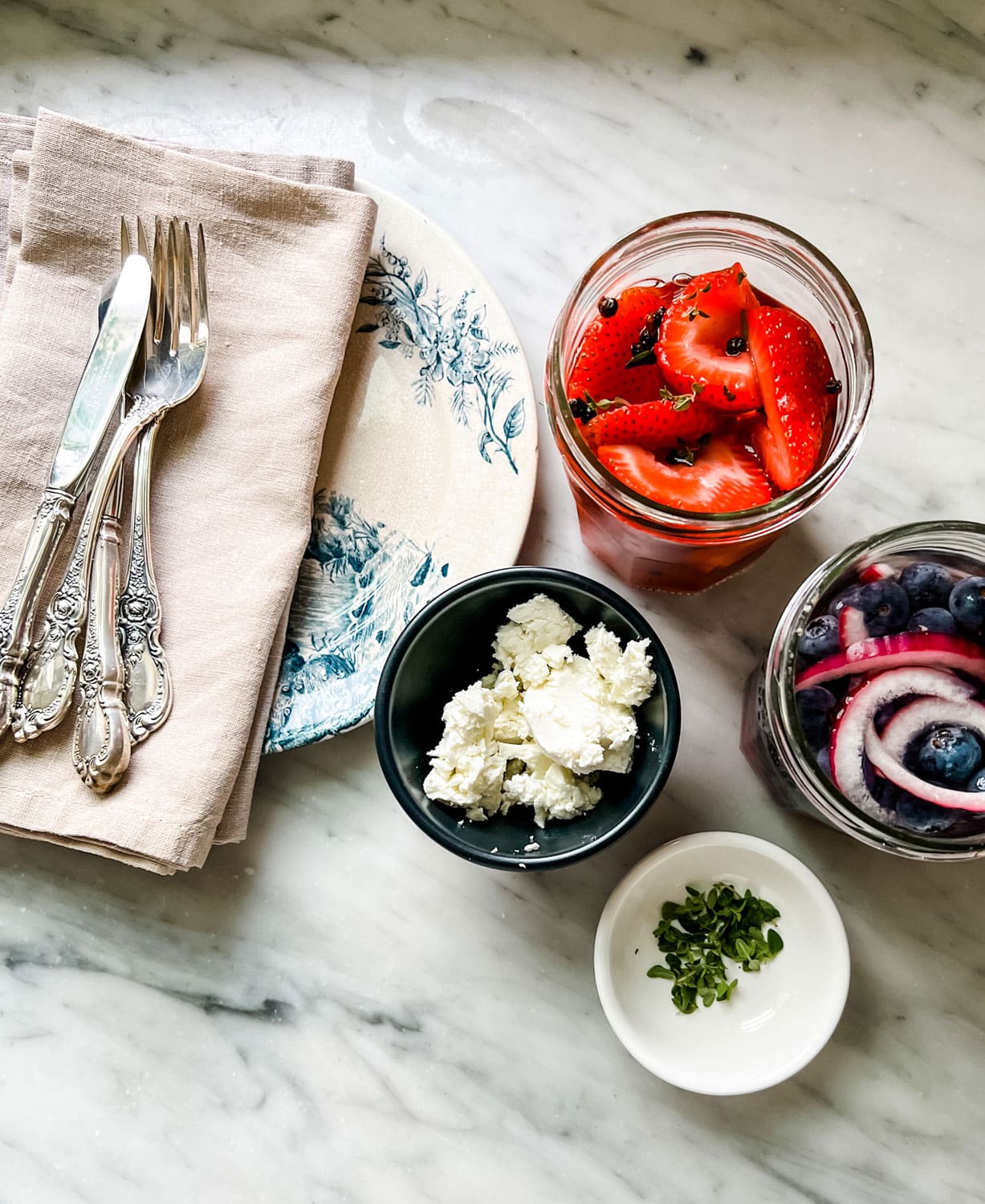  pickled strawberries and blueberries.peppercorns, vinegar, red onion, plates, silverware, chèvre 