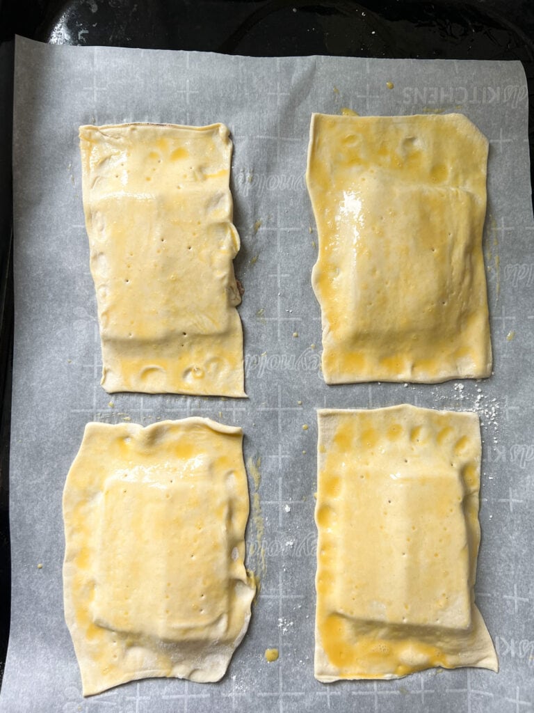 Puff pastry squares with egg wash on parchemnt paper