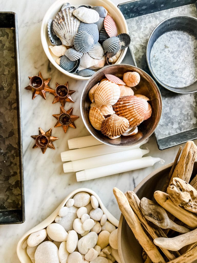 shells, white ticks driftwood, candles in bowls on marble counter