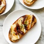 Toast with cheese, fig jam and fresh thyme on white plates