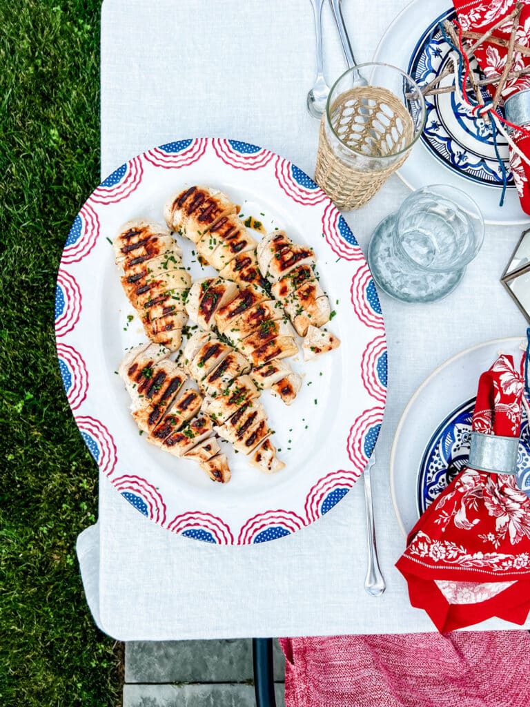 buttermilk grilled chicken and putting it on a Fourth of July USA flag platter on a festive table with red print napkins