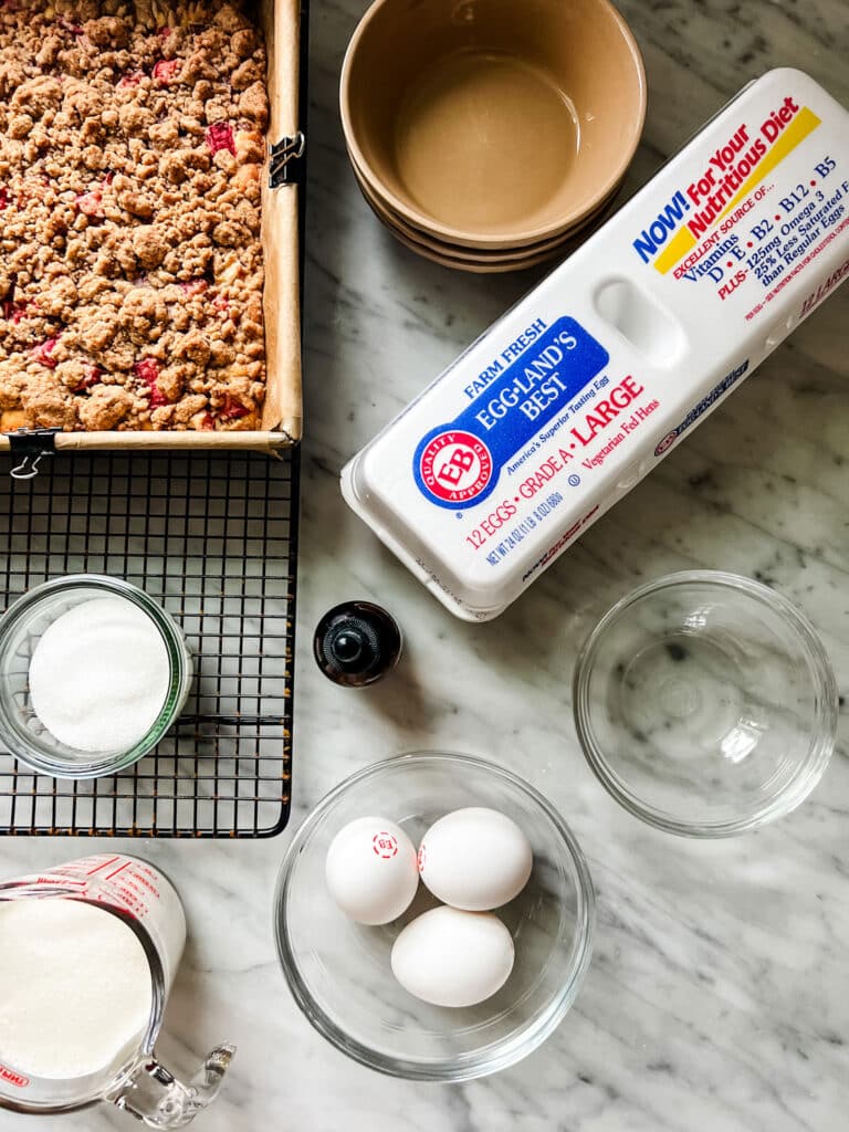 ingredients, egg carton, pan of crumb bars The Best Rhubarb Crumb Bar Recipe With Vanilla Cream