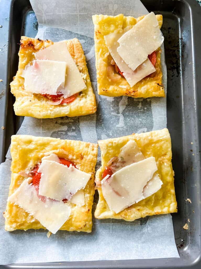  upside-down tarts with shards of parmesan on baking sheet with white parchment paper 