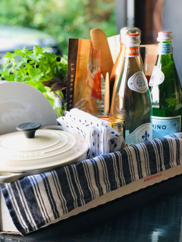 Le Creuset, glass bottles of water, herbs, bread in bag