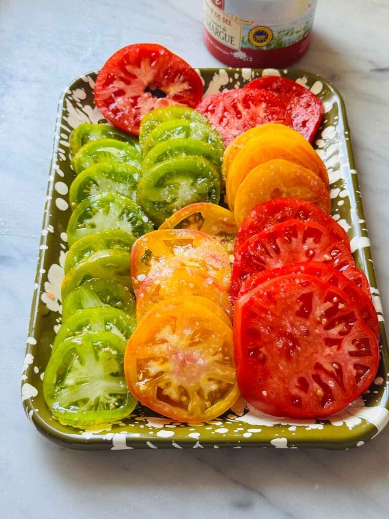 A variety of vine-ripened tomatoes haven been cored and sliced and have been placed on a small tray. 