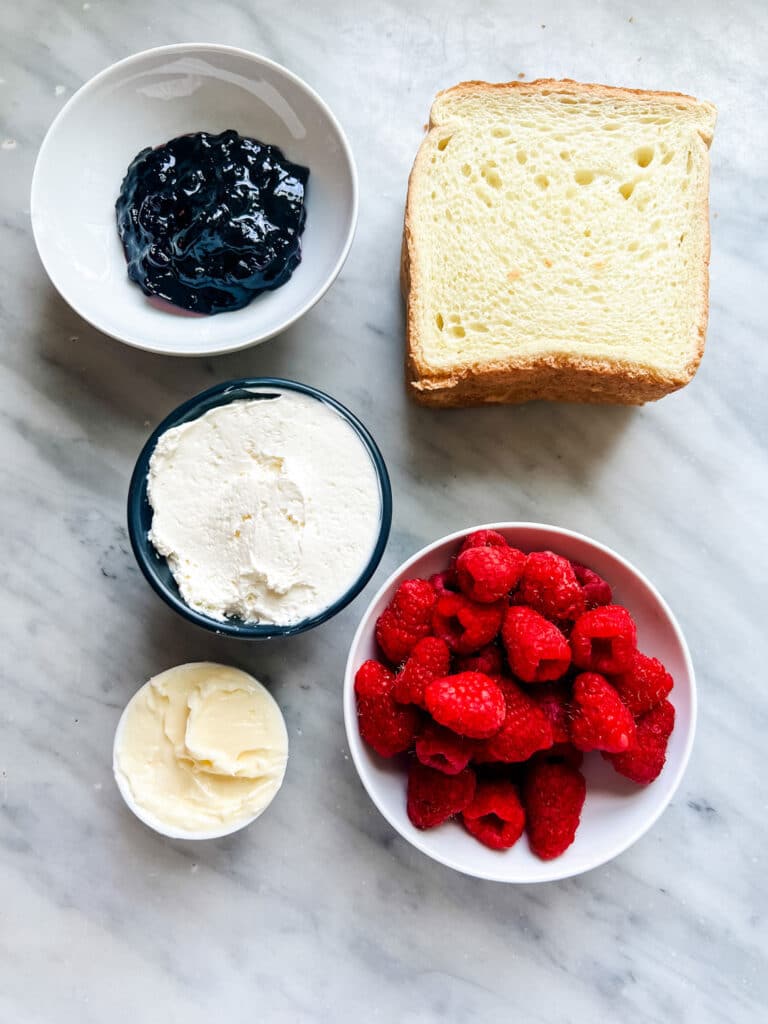 bread, small bowls with jam, cream cheese, butter, rasperries 