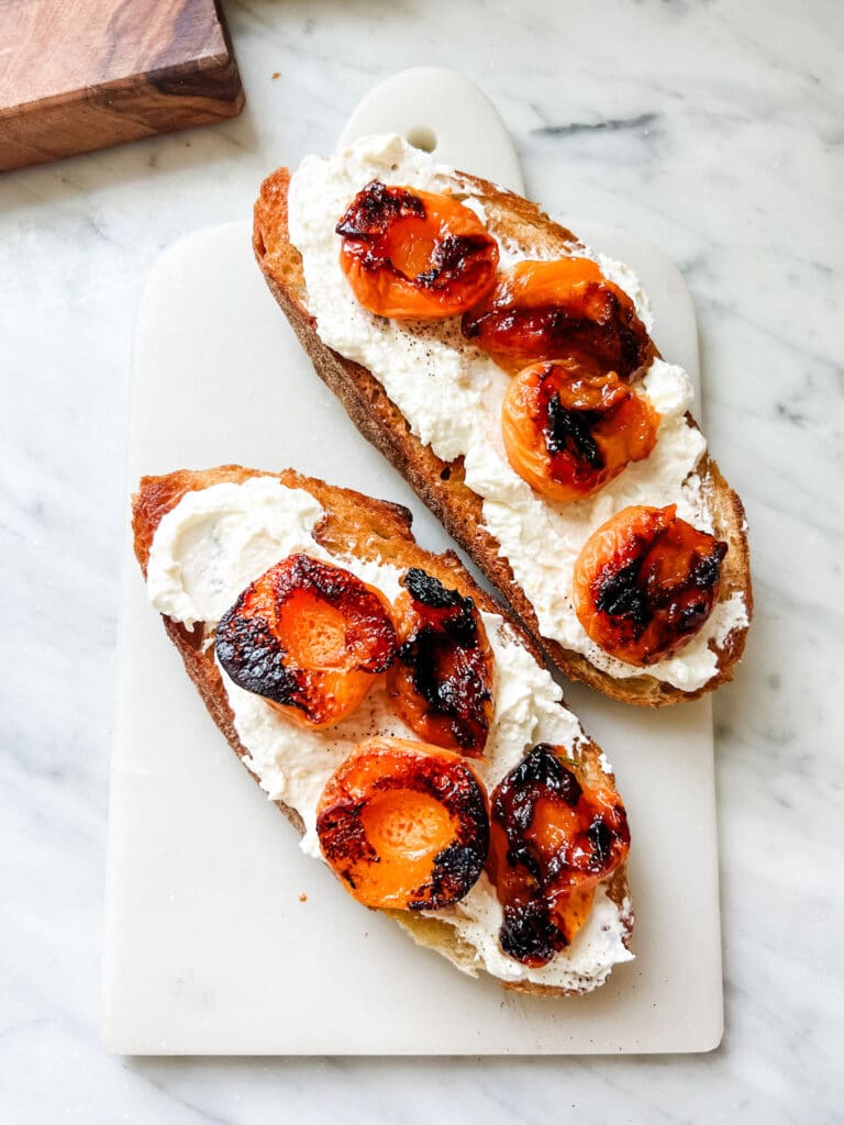 Caramelized apricots and fresh ricotta tartine on white marble board