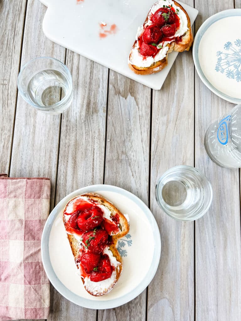 Balsamic Strawberries with Creamy Goat Cheese on a Tartine on teak table with rose checked napkins