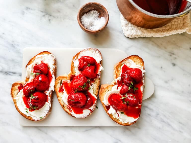 Strawberry, creamy goat cheese, and balsamic tartines are a marble cutting board.