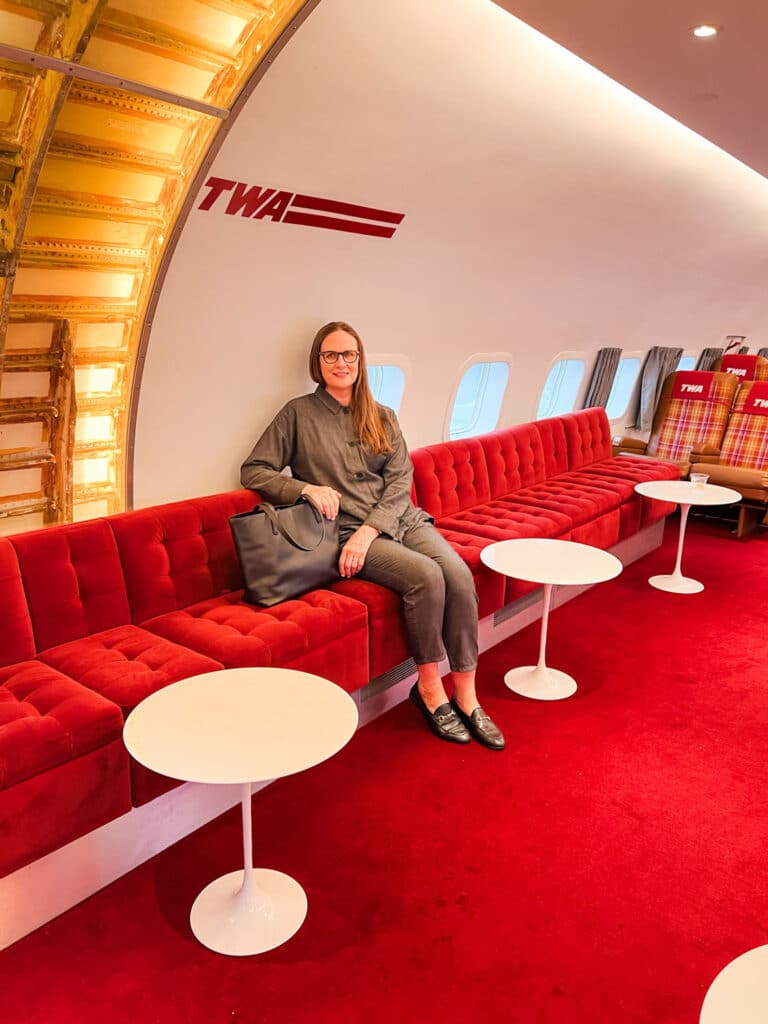 TWA hotel at JFK. I'm wearing a 2-piece outfit -older woman seated in small airplane 
