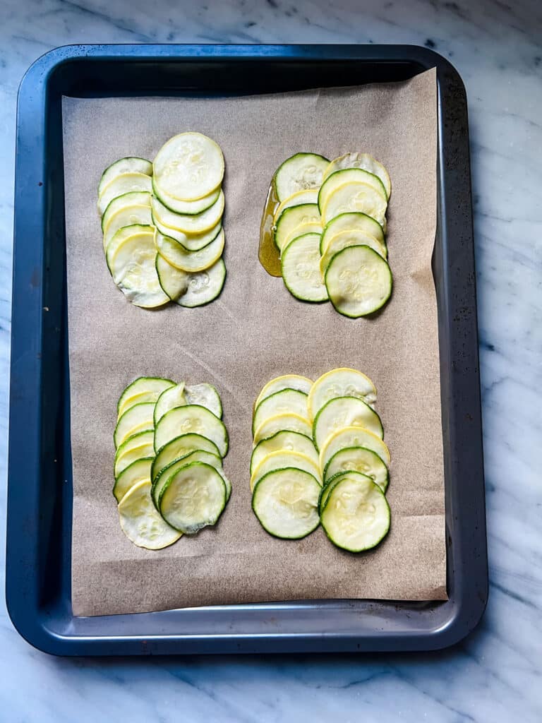 Extra Virgin Olive Oil on Parchment, with rows of thinly sliced zucchini and yellow squash