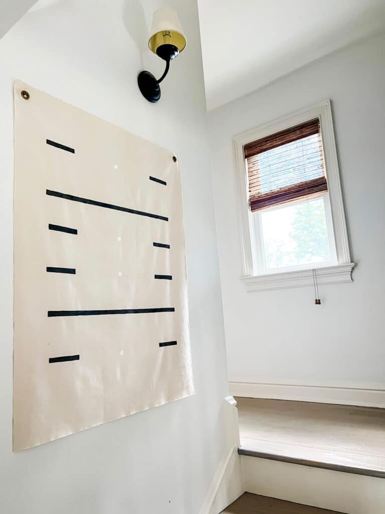 A large piece of canvas with black and white stripes painted on and small white dos running down the middle of the canvas
