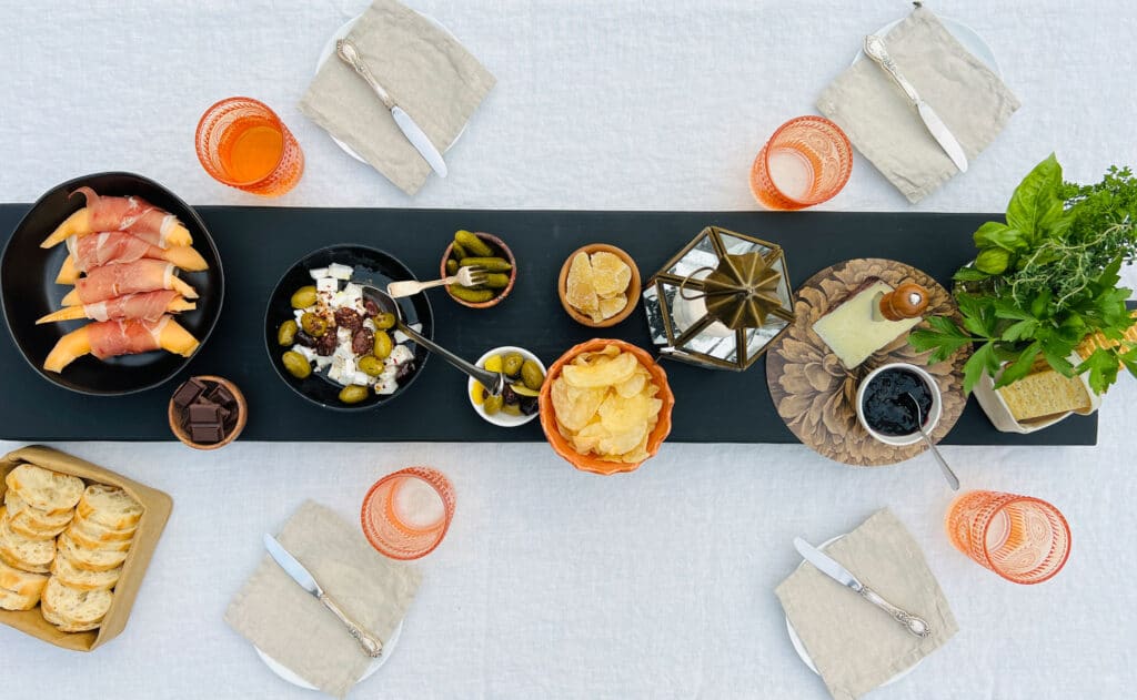 White tablecloth and black farmtable plank on top with cheese and charcuterie