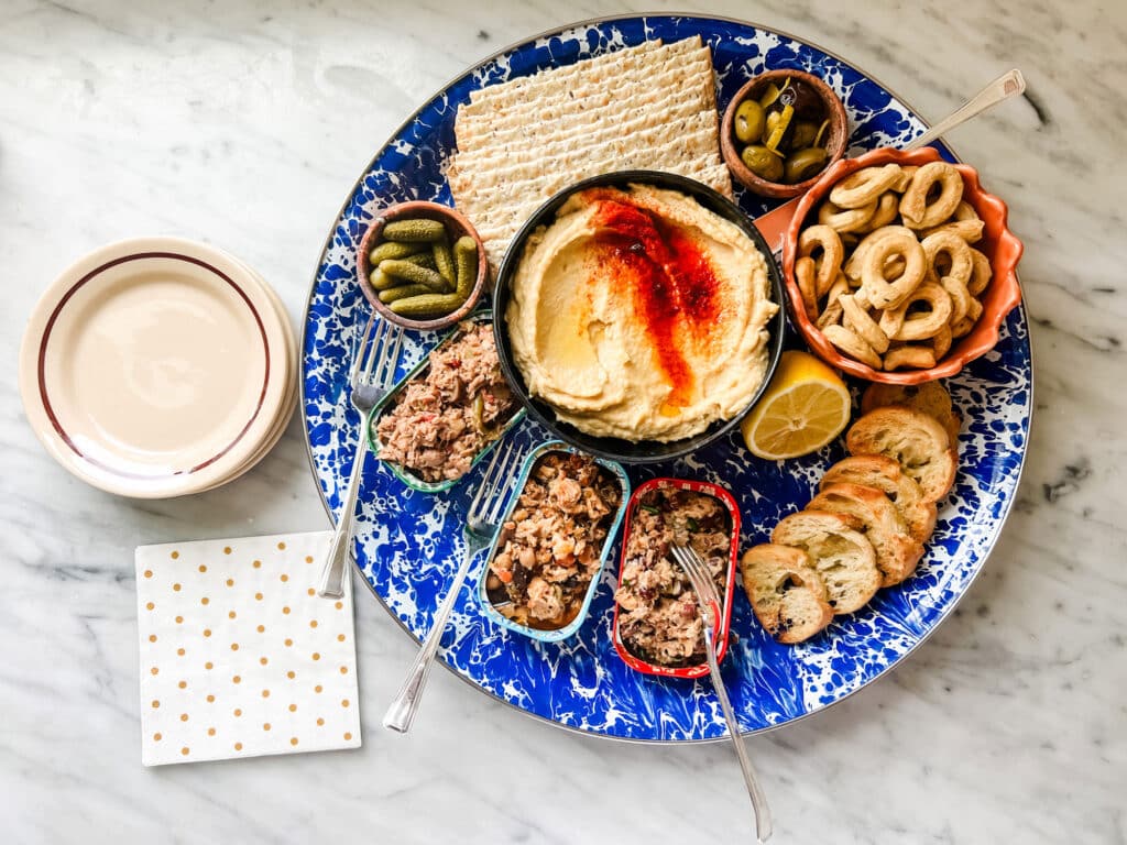 blue and white round tray with tinned fish and hummus