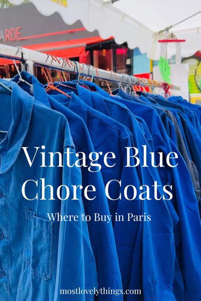 A rack with many vintage blue chore coats hanging in a long row.