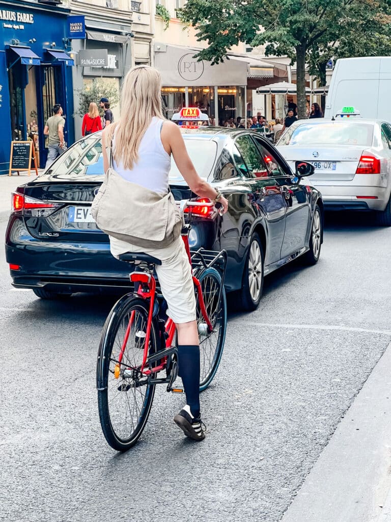 woman wearing Sambas and black knee socks with cross body messenger bag one her bike.