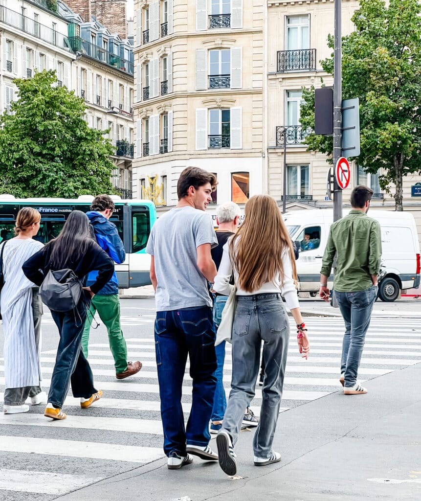 A young couple, both wearing white with black stripe OG Sambas in a Paris street.